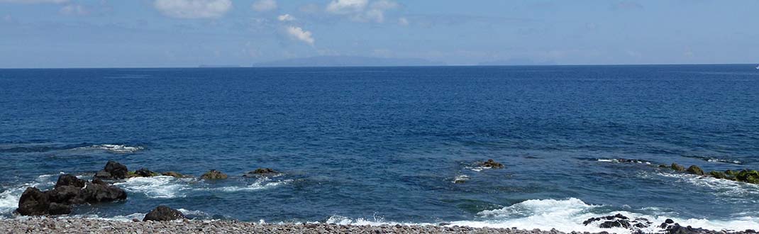 blaues Meer mit Wischereffekt für Unschärfe, Vordergrund steiniger Strand und Felsen